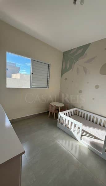 Quarto infantil clean com cama montessoriana, mesa redonda e decoração minimalista em tons neutros.