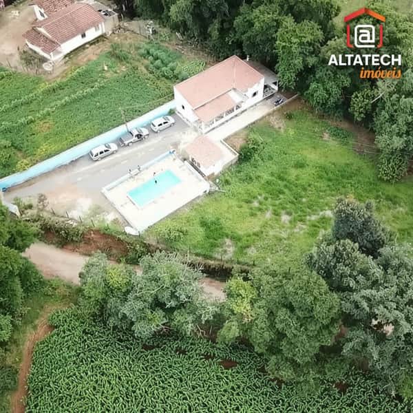 Vista aérea de casa com piscina, área verde e carros estacionados. Destaque para o lazer e espaço externo.