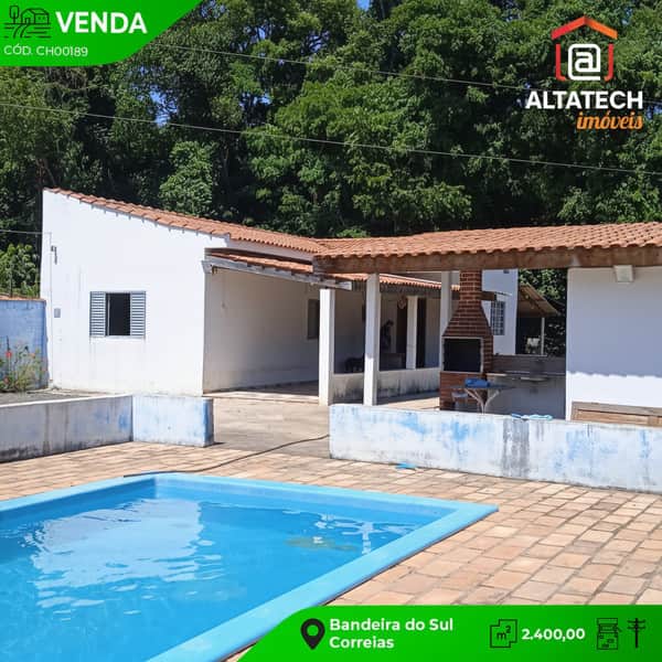 Casa com piscina e churrasqueira. Área externa com piso de tijolos e construção branca com telhado.