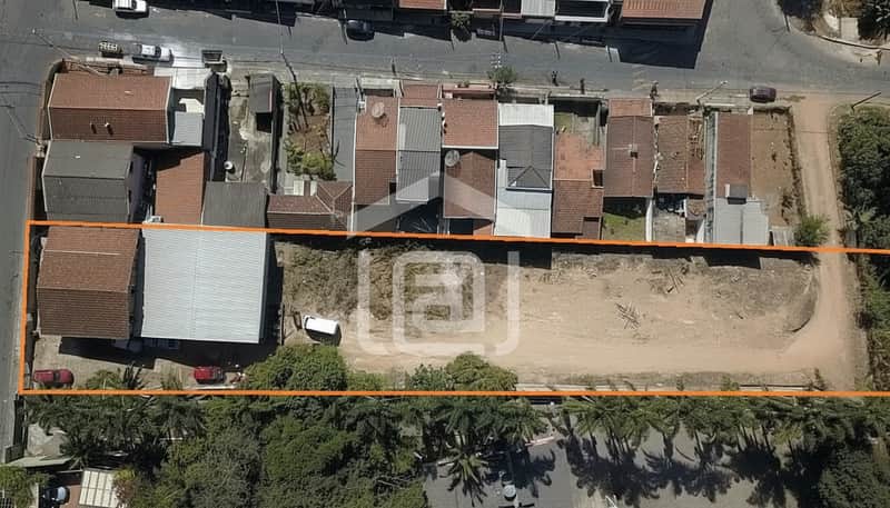 Terreno retangular murado com vegetação e casas ao redor. Espaço amplo e plano com terra batida.