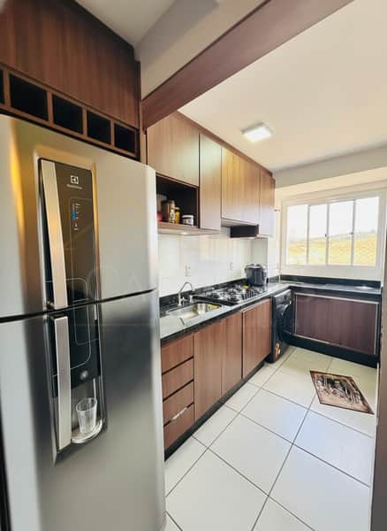 Cozinha moderna com armários marrons, geladeira inox e piso branco. Ambiente clean e bem iluminado.