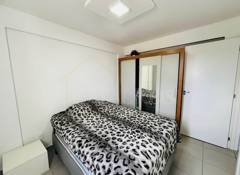 Quarto com cama estampada, guarda-roupa espelhado e piso cerâmico claro. Ambiente clean e iluminado.
