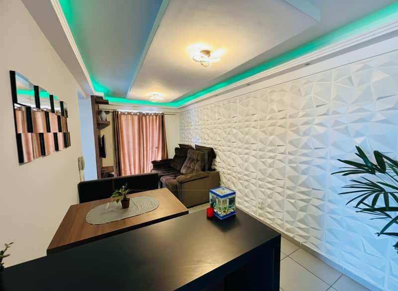 Sala moderna com iluminação verde no teto, parede 3D e móveis em tons de marrom e preto.