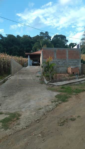 Área externa com rampa de acesso à garagem. Construção em blocos e vegetação ao redor. Céu azul.