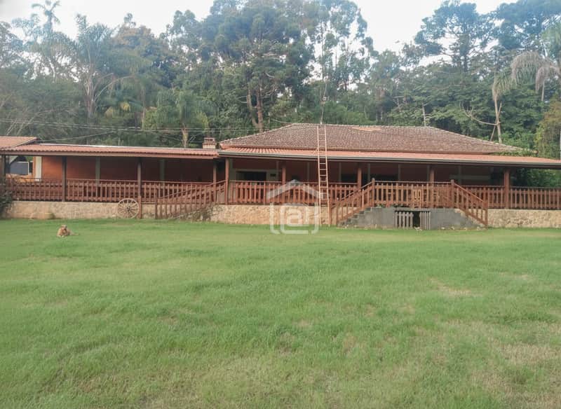 Casa rústica com varanda, jardim amplo e gramado. Arquitetura charmosa em área externa arborizada.