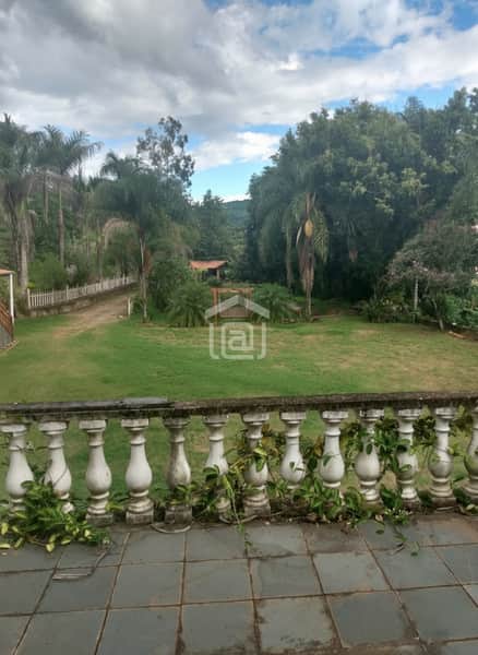 Varanda com vista para jardim gramado e árvores. Parapeito de pedra com vegetação. Piso em cerâmica.