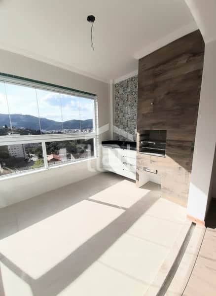 Sala com churrasqueira, janela ampla com vista para a cidade, piso claro e armários planejados.