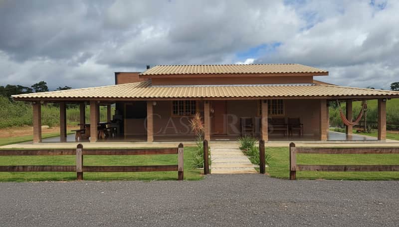 Fachada de casa térrea com varanda, cerca de madeira e gramado. Estilo rústico e aconchegante.
