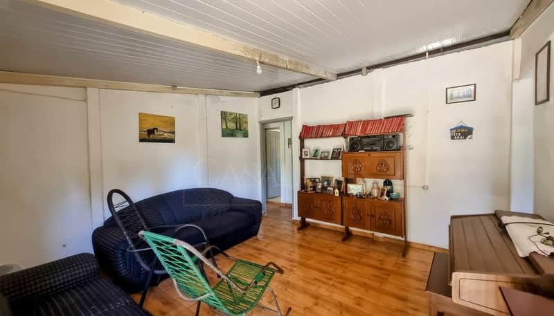 Sala rústica com sofá azul, cristaleira antiga e piso de madeira. Decoração simples e aconchegante.