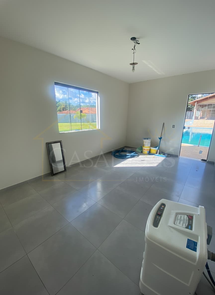 Sala ampla com piso cinza, janela com vista para o jardim e piscina ao fundo.