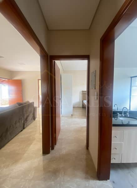 Interior de imóvel. Corredor com acesso à sala, quarto e banheiro. Acabamento em mármore.