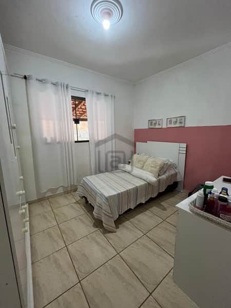 Quarto simples com cama de solteiro, piso cerâmico e armário branco. Decoração minimalista e iluminação suave.